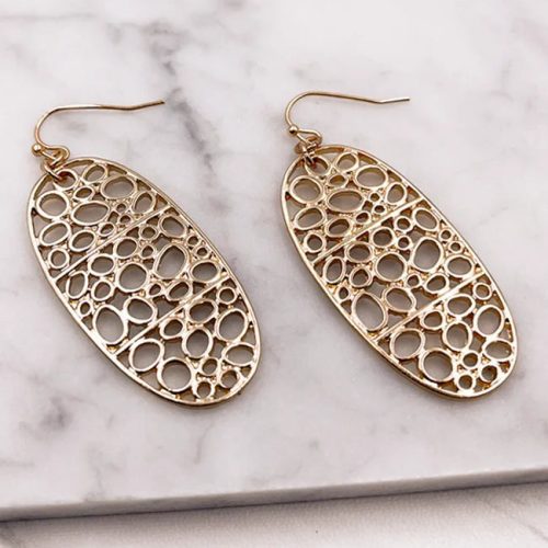 Gold bubbles oval earrings with circular design displayed on a marble surface