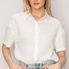 White short-sleeved button-up shirt tucked into light blue jeans for a boho free spirit look