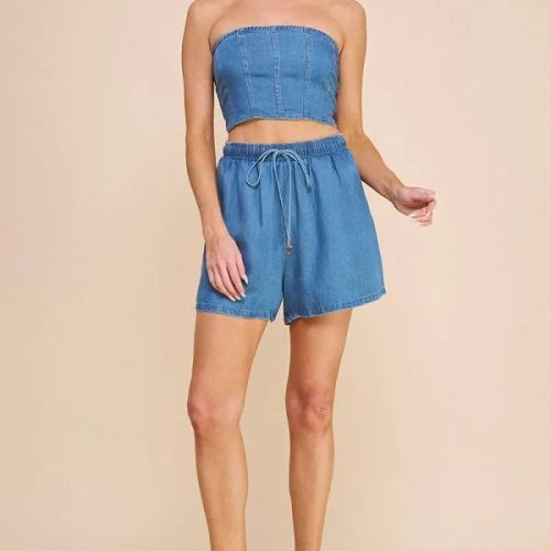 Woman in a blue strapless crop top and washed denim high waisted tie shorts