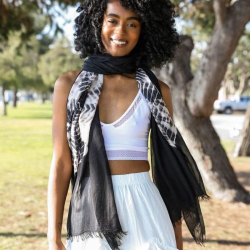 Woman in a white dress showcasing a Tie Dye Lightweight Scarf with a black scarf